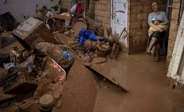 Dolores Merchan, 67, looks down on her mud-splattered belongings from the house where she has lived all her life with her husband and three children, and which has been severely affected by the floods in Masanasa, Valencia, Spain, Thursday, Nov. 7, 2024. (AP Photo/Emilio Morenatti)