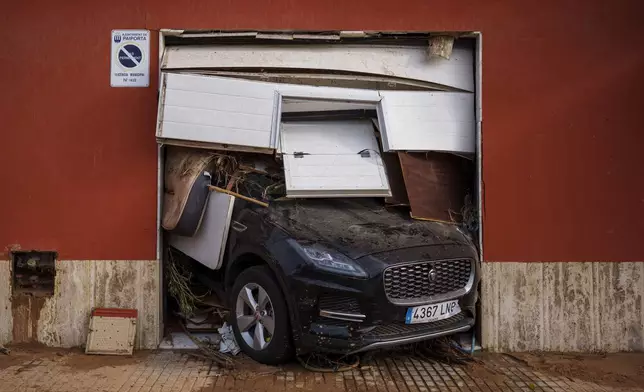 A car sticks out of a garage with debris after flooding in Valencia, Spain, Saturday, Nov. 2, 2024. (AP Photo/Manu Fernandez)