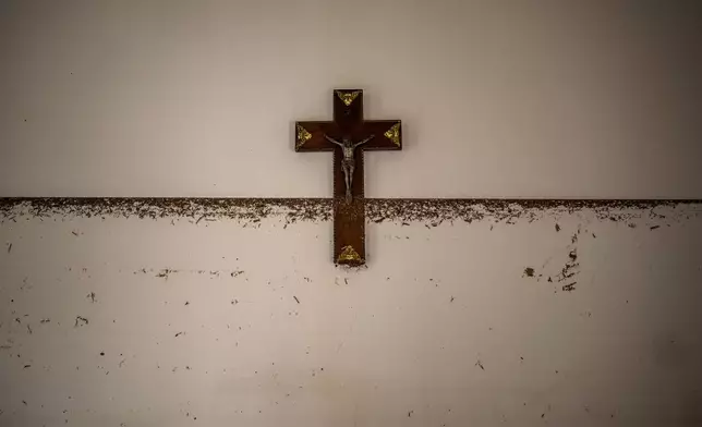 A crucifix hangs near the water level marker in an area affected by floods in Paiporta, Valencia, Spain, Tuesday, Nov. 5, 2024. (AP Photo/Emilio Morenatti)