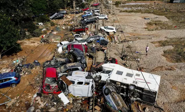 A man stands next to flooded cars piled up in Valencia, Spain, Thursday, Oct. 31, 2024. (AP Photo/Manu Fernandez)