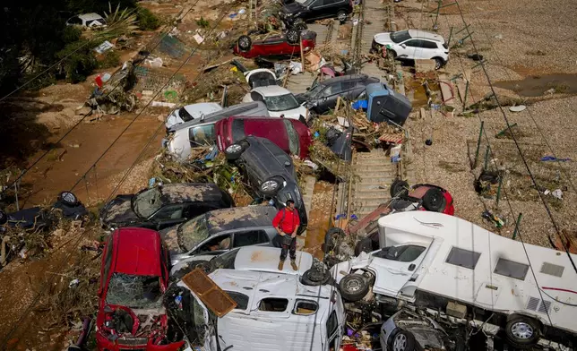 A man stands among flooded cars piled up in Valencia, Spain, Thursday, Oct. 31, 2024. (AP Photo/Manu Fernandez)