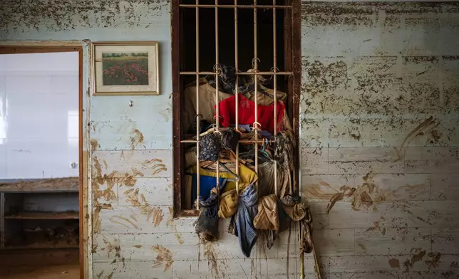 Wet clothes hangs on a window near the water level marker in an area affected by floods in Paiporta, Valencia, Spain, Tuesday, Nov. 5, 2024. (AP Photo/Emilio Morenatti)