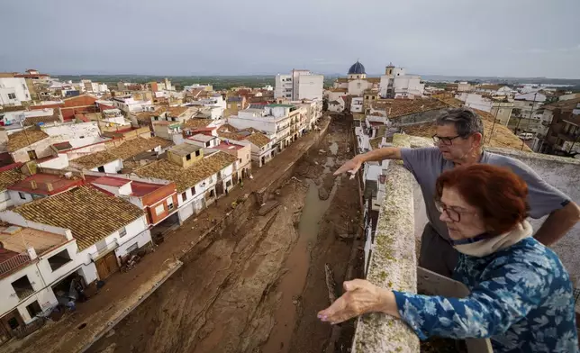 Two people look out over an area affected by floods in Chiva, Spain, Friday, Nov. 1, 2024. (AP Photo/Manu Fernandez)