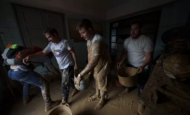 People clean a house of mud in an area affected by floods in Sedavi, Spain, on Friday, Nov. 1, 2024. (AP Photo/Manu Fernandez)