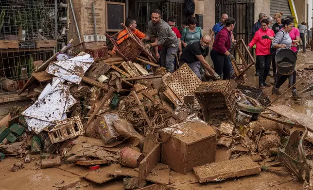 People clean mud from a shop affected by floods in Chiva, Spain, Friday, Nov. 1, 2024. (AP Photo/Manu Fernandez)