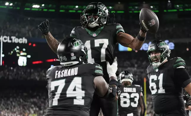 New York Jets offensive tackle Olu Fashanu (74) lifts wide receiver Davante Adams (17) after his touchdown during the second half of an NFL football game against the Houston Texans, Thursday, Oct. 31, 2024, in East Rutherford, N.J. (AP Photo/Frank Franklin II)