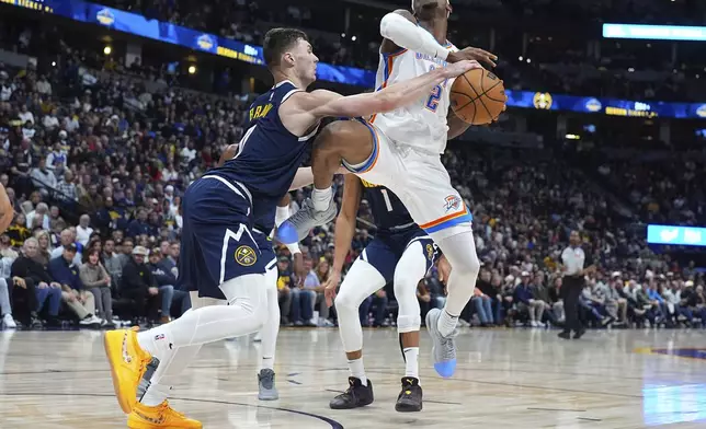 Denver Nuggets guard Christian Braun, left, fouls Oklahoma City Thunder guard Shai Gilgeous-Alexander as he drives the land in the second half of an NBA basketball game Wednesday, Nov. 6, 2024, in Denver. (AP Photo/David Zalubowski)