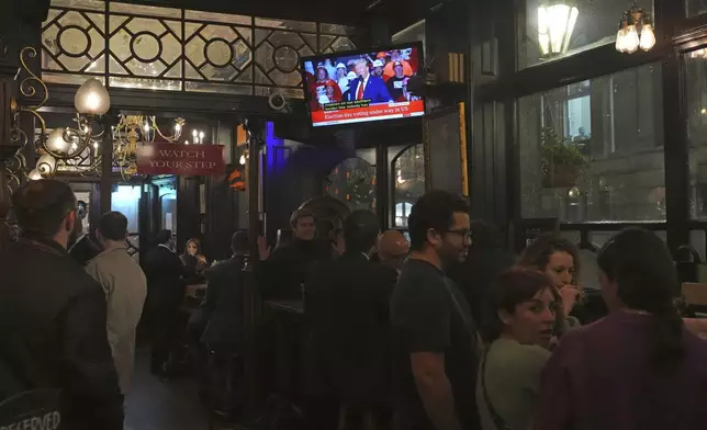 People in a London pub follow the news on TV screens about the U.S. election, Tuesday, Nov. 5, 2024. (AP Photo/Frank Augstein)