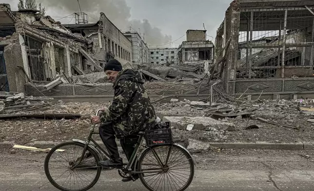 A man rides on a bike in front of the mail office which was destroyed by a Russian airstrike in Kurakhove, Donetsk region, Ukraine, on Nov. 7, 2024. (AP Photo/Anton Shtuka)