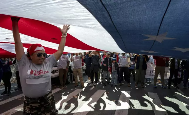 People carry the American flag during the annual Veterans Day Parade, Monday, Nov. 11, 2024 in New York. (AP Photo/Adam Gray)