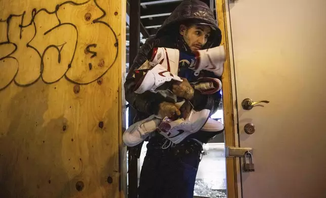 A person carries out items from a ransacked Nike store after the Los Angeles Dodgers defeated the New York Yankees to win the baseball World Series Wednesday, Oct. 30, 2024, in Los Angeles. (AP Photo/Ethan Swope)