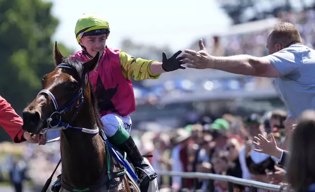 Jockey Robbie Dolan, left, celebrates with a fan after riding Knight's Choice to win the Melbourne Cup horse race at Flemington Racecourse in Melbourne, Australia, Tuesday, Nov. 5, 2024. (AP Photo/Asanka Brendon Ratnayake)