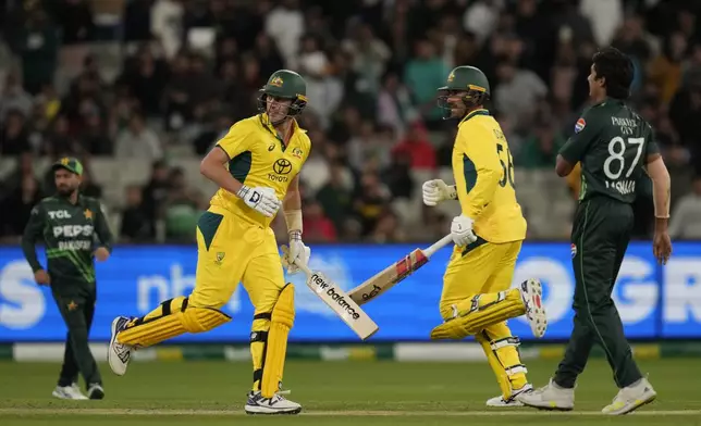 Australia's Pat Cummins, second left, and Australia's Mitchell Starc, second right, cross as they score the winning run off the bowling of Pakistan's Mohammad Hasnain, right, during their one day international cricket match in Melbourne, Monday, Nov. 4, 2024. (AP Photo/Asanka Brendon Ratnayake)