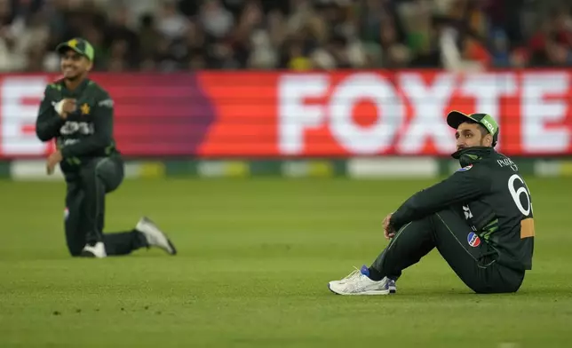 Pakistan's Aamer Jamal, right, sits on the ground after after a missed chance to run out Australia's Pat Cummins during their one day international cricket match in Melbourne, Monday, Nov. 4, 2024. (AP Photo/Asanka Brendon Ratnayake)