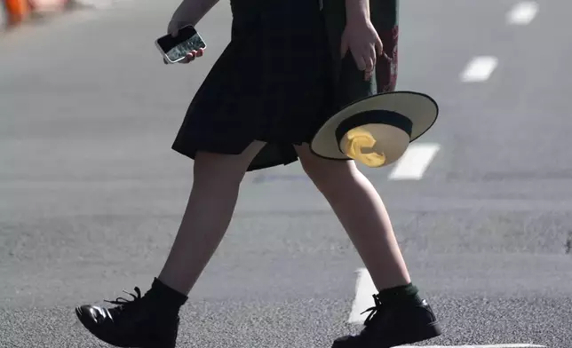 A school girl holds her phone while crossing a street in Sydney, Friday, Nov. 8, 2024. (AP Photo/Rick Rycroft)