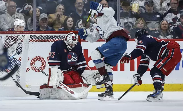 Colorado Avalanche's Artturi Lehkonen (62) jumps out of the way of the shot on Winnipeg Jets goaltender Connor Hellebuyck (37) as Josh Morrissey (44) defends during the second period of an NHL hockey game Thursday, Nov. 7, 2024 in Winnipeg, Manitoba. (John Woods/The Canadian Press via AP)