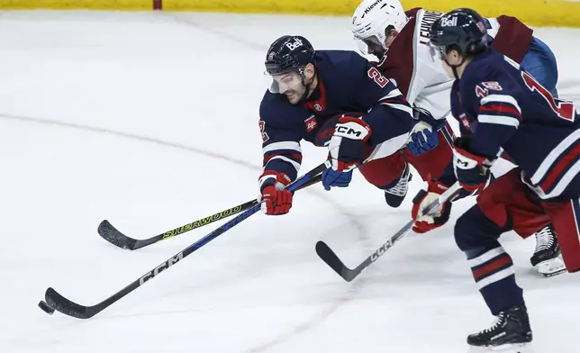 Winnipeg Jets' Dylan DeMelo (2) clears the puck as he defends against Colorado Avalanche's Artturi Lehkonen (62) during the third period of an NHL hockey game Thursday, Nov. 7, 2024 in Winnipeg, Manitoba. (John Woods/The Canadian Press via AP)