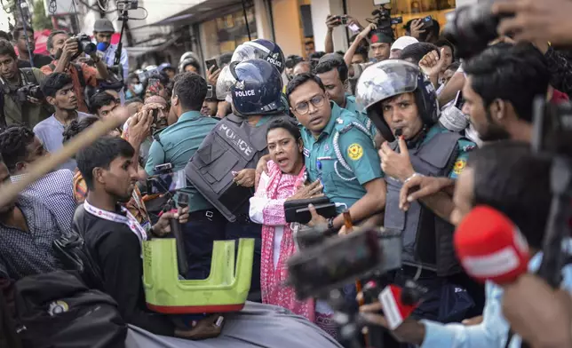 A police officer shields an Awami League woman supporter from students from anti-discrimination movements in Dhaka, Bangladesh, Sunday, Nov. 10, 2024. (AP Photo/Mahmud Hossain Opu)