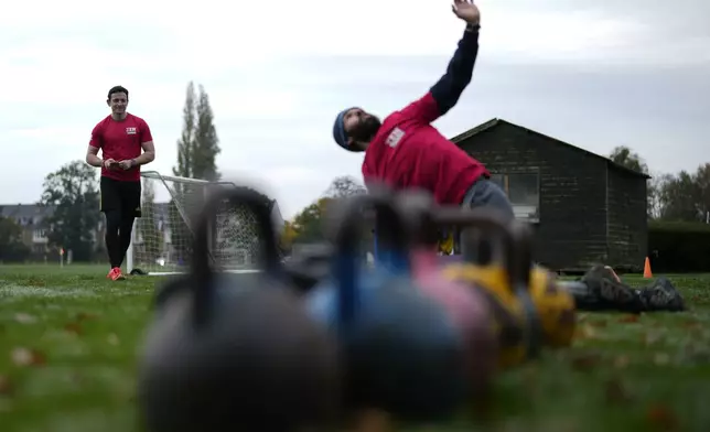 Owner of a personal fitness company Zen Training, Alan Ezen, left, watches his trainer Richard Lamb, lead an outdoor gym class in London, Saturday, Oct. 26, 2024. (AP Photo/Alastair Grant)