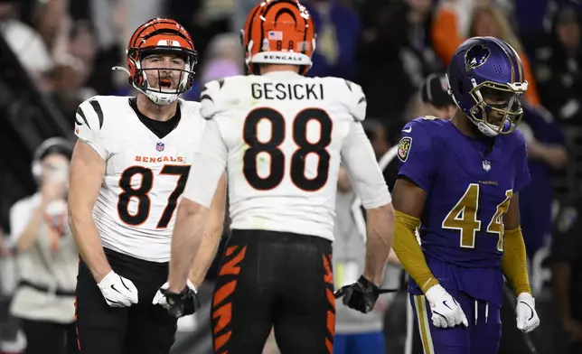 Cincinnati Bengals tight end Tanner Hudson (87) celebrates scoring a touchdown with tight end Mike Gesicki (88) as Baltimore Ravens cornerback Marlon Humphrey (44) walks right during the first half of an NFL football game, Thursday, Nov. 7, 2024, in Baltimore. (AP Photo/Nick Wass)