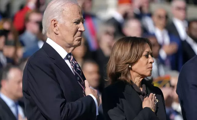 President Joe Biden, left, and Vice President Kamala Harris look on during a wreath laying ceremony at the Tomb of the Unknown Soldier on National Veterans Day Observance at Arlington National Cemetery in Arlington, Va., Monday, Nov. 11, 2024. (AP Photo/Mark Schiefelbein)