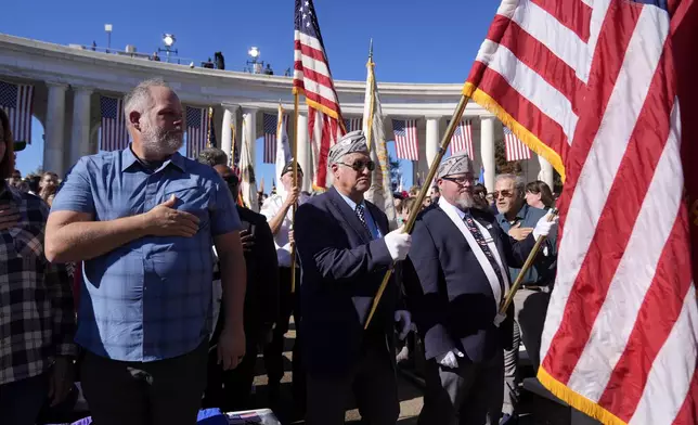 Attendees look on during the Presentation of the Colors at the National Veterans Day Observance at the Memorial Amphitheater at Arlington National Cemetery in Arlington, Va., Monday, Nov. 11, 2024. (AP Photo/Mark Schiefelbein)