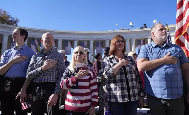 Attendees look on during the Presentation of the Colors at the National Veterans Day Observance at the Memorial Amphitheater at Arlington National Cemetery in Arlington, Va., Monday, Nov. 11, 2024. (AP Photo/Mark Schiefelbein)