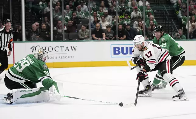 Dallas Stars goaltender Jake Oettinger (29) slaps a puck away on an attack by Chicago Blackhawks' Nick Foligno (17) as Thomas Harley (55) helps defend on the play in the second period of an NHL hockey game in Dallas, Thursday, Nov. 7, 2024. (AP Photo/Tony Gutierrez)