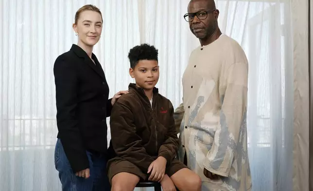 Steve McQueen, right, writer/director of "Blitz," poses with cast members Saoirse Ronan, left, and Elliott Heffernan at the Four Seasons Hotel, Monday, Oct. 14, 2024, in Los Angeles. (AP Photo/Chris Pizzello)