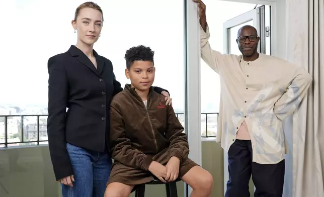 Steve McQueen, right, writer/director of "Blitz," poses with cast members Saoirse Ronan, left, and Elliott Heffernan at the Four Seasons Hotel, Monday, Oct. 14, 2024, in Los Angeles. (AP Photo/Chris Pizzello)