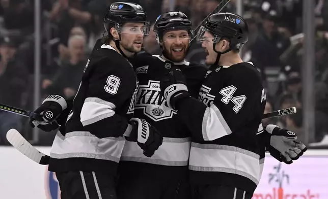 Los Angeles Kings defenseman Vladislav Gavrikov (84) celebrates scoring a goal with right wing Adrian Kempe (9) and defenseman Mikey Anderson (44) against the Columbus Blue Jackets during the second period of an NHL hockey game in Los Angeles, Saturday, Nov. 9, 2024. (AP Photo/Alex Gallardo)