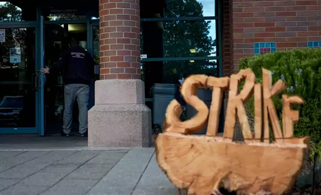 A Boeing employee walks by a sign carved out of wood while arriving to vote on a new contract offer from the company, Wednesday, Oct. 23, 2024, at Seattle Union Hall in Seattle. (AP Photo/Lindsey Wasson)