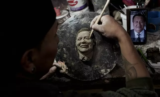 Artisan William Luna creates a mask of a loved one for the Mendoza family to adorn a piece of tantawawa, a sweet bread traditional for Day of the Dead celebrations, in La Paz, Bolivia, Thursday, Oct. 31, 2024. (AP Photo/Freddy Barragan)