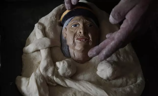 Artisan William Luna places a plaster mask of his grandmother on a piece of tantawawa bread during Day of the Dead celebrations in La Paz, Bolivia, Thursday, Oct. 31, 2024. (AP Photo/Freddy Barragan)