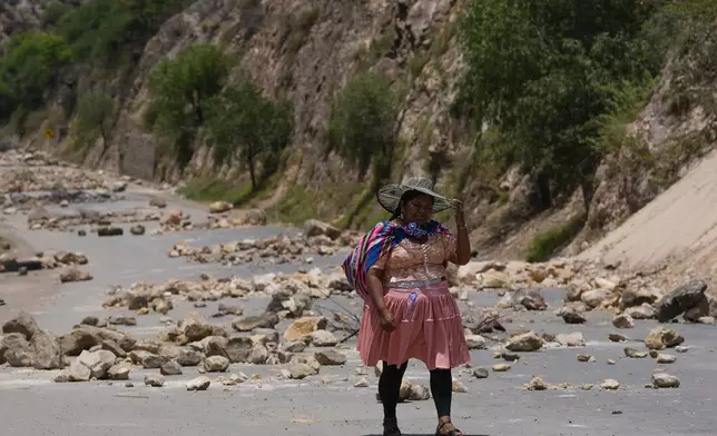 A woman traverses a road blocked by supporters of former President Evo Morales to prevent him from facing a criminal investigation over allegations of abuse of a minor and to demonstrate against an alleged assassination attempt, in Parotani, Bolivia, Thursday, Oct. 31, 2024. (AP Photo/Juan Karita)