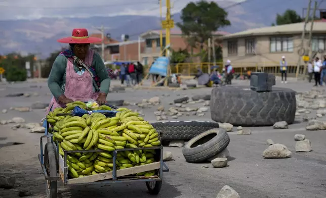 A woman pushes a banana cart as supporters of Bolivian former President Evo Morales block roads to prevent him from facing a criminal investigation over allegations of abuse of a minor and to demonstrate against an alleged assassination attempt, near Cochabamba, Bolivia, Monday, Oct. 28, 2024. (AP Photo/Juan Karita)