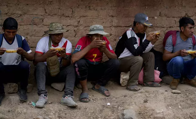 Supporters of former President Evo Morales have a meal while blocking a road to prevent him from facing a criminal investigation over allegations of abuse of a minor and to demonstrate against an alleged assassination attempt, in Parotani, Bolivia, Thursday, Oct. 31, 2024. (AP Photo/Juan Karita)