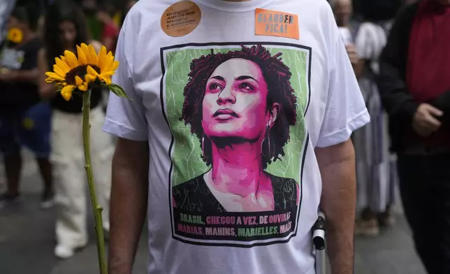 An activist wearing a T-shirt with the image of former city councilwoman Marielle Franco attends a rally prior to the trial for Franco's alleged killers, outside the Court of Justice, in Rio de Janeiro, Wednesday, Oct. 30, 2024. (AP Photo/Silvia Izquierdo)