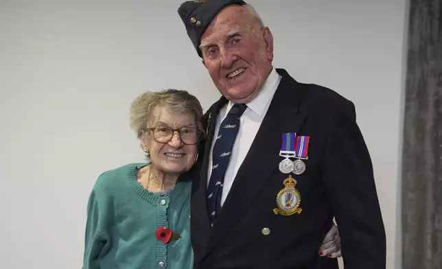 Michael Woods, 100-year-old World War II veteran, poses with his wife Mary during an interview in Dunstable, Bedfordshire, England, Tuesday, Nov. 5, 2024. (AP Photo/Kin Cheung)