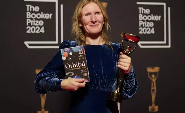 Samantha Harvey poses with the trophy and her book "Orbital" after winning the Booker Prize award 2024, in London, Tuesday, Nov. 12, 2024. (AP Photo/Alberto Pezzali)