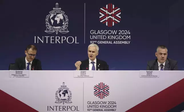 Juergen Stock Interpol secretary general, center, Graeme Biggar National crime agency director general, left, and Samuel Heath Interpol communications director, right, address the media at 92nd Interpol general assembly in Glasgow, Scotland, Monday, Nov. 4, 2024. (AP Photo/Scott Heppell)