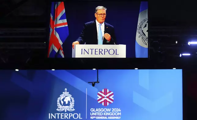 Britain's Prime Minister Keir Starmer, seen on a large video screen, speaking at the opening ceremony for the Interpol General Assembly in Glasgow, Scotland Monday, Nov. 4, 2024. (AP Photo/Scott Heppell)