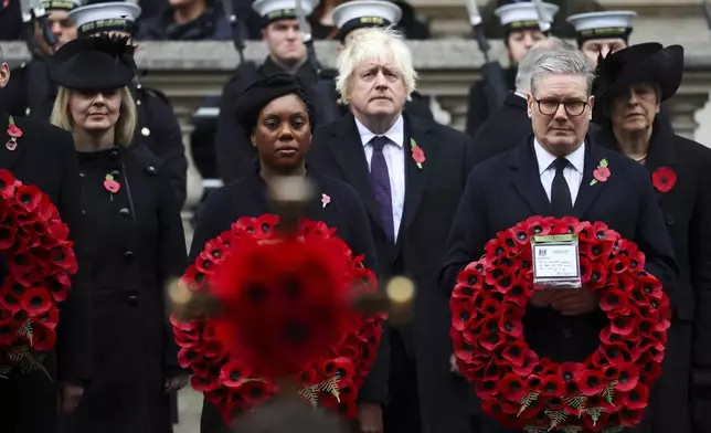 British Prime Minister Keir Starmer, front right, and Conservative Party leader Kemi Badenoch, front left, carry wreaths, as former Prime Ministers Boris Johnson, second row center, Liz Truss, second row left, and Theresa May, second row right, look on as they attend the annual Remembrance Sunday ceremony at The Cenotaph in London, England, Sunday, Nov. 10, 2024. (Toby Melville/Pool Photo via AP)