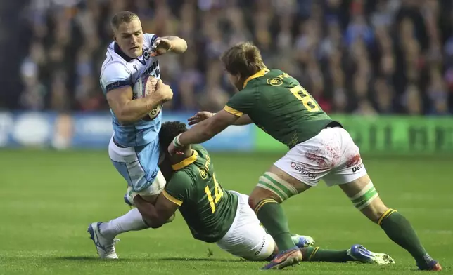 Scotland's Duhan van der Merwe, left is tackled by South Africa's Canan Moodie and his teammate South Africa's Kwagga Smith, right, during the Autumn Nations series rugby union match between Scotland and South Africa in Edinburgh, Scotland, Sunday, Nov. 10, 2024. (AP Photo/Scott Heppell)