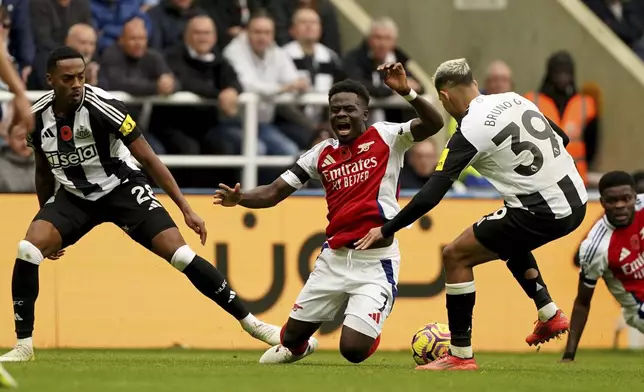 Arsenal's Bukayo Saka, center, is fouled by Newcastle United's Joe Willock, left, during the English Premier League soccer match between Newcastle United and Arsenal, at St James' Park, in Newcastle, England, Saturday, Nov. 2, 2024. (Owen Humphreys/PA via AP)