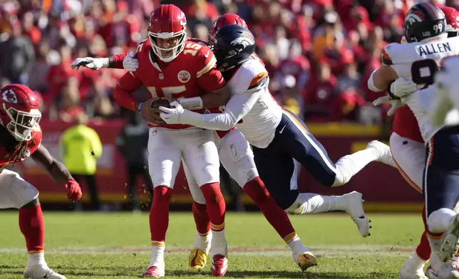 Kansas City Chiefs quarterback Patrick Mahomes (15) is stopped by Denver Broncos outside linebacker Jonathon Cooper, right, during the first half of an NFL football game Sunday, Nov. 10, 2024, in Kansas City, Mo. (AP Photo/Ed Zurga)