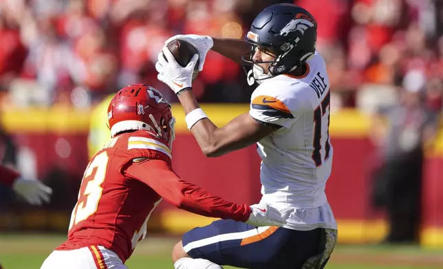 Denver Broncos wide receiver Devaughn Vele (17) catches a pass as Kansas City Chiefs safety Nazeeh Johnson (13) defends during the first half of an NFL football game Sunday, Nov. 10, 2024, in Kansas City, Mo. (AP Photo/Charlie Riedel)