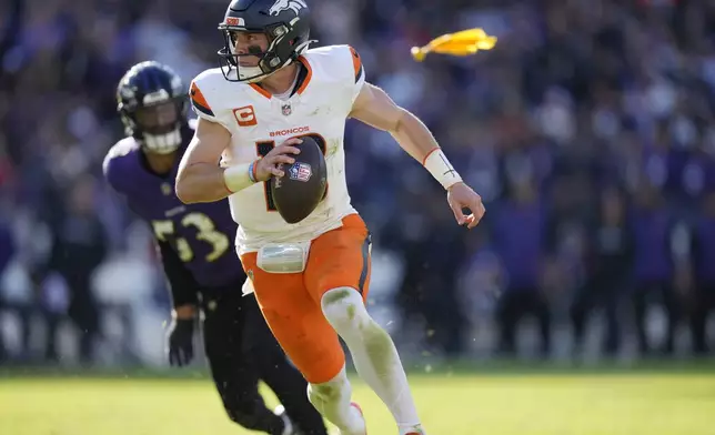 Denver Broncos quarterback Bo Nix, front, eludes a tackle by Baltimore Ravens linebacker Kyle Van Noy, back, in the first half of an NFL football game Sunday, Nov. 3, 2024, in Baltimore. (AP Photo/Stephanie Scarbrough)