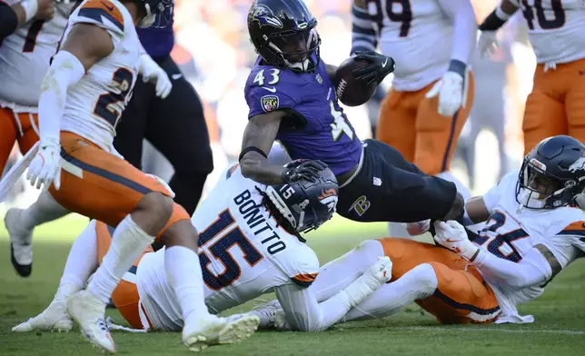 Baltimore Ravens running back Justice Hill (43) is stopped by Denver Broncos linebacker Nik Bonitto (15) and safety Devon Key (26) after a short gain in the second half of an NFL football game Sunday, Nov. 3, 2024, in Baltimore. (AP Photo/Nick Wass)