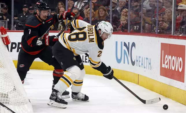 Boston Bruins' Elias Lindholm (28) controls the puck in front of Carolina Hurricanes Dmitry Orlov (7) during the first period of an NHL hockey game in Raleigh, N.C., Thursday, Oct. 31, 2024. (AP Photo/Karl B DeBlaker)